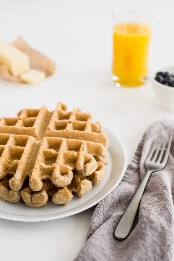 Whole Wheat Waffle Recipe with Warm Peach Sauce - these whole grain waffles are deliciously fluffy and light thanks to whipped egg whites in the batter! A homemade peach sauce makes them the perfect weekend brunch, but they're also freezer-friendly for easy weekday breakfasts! 