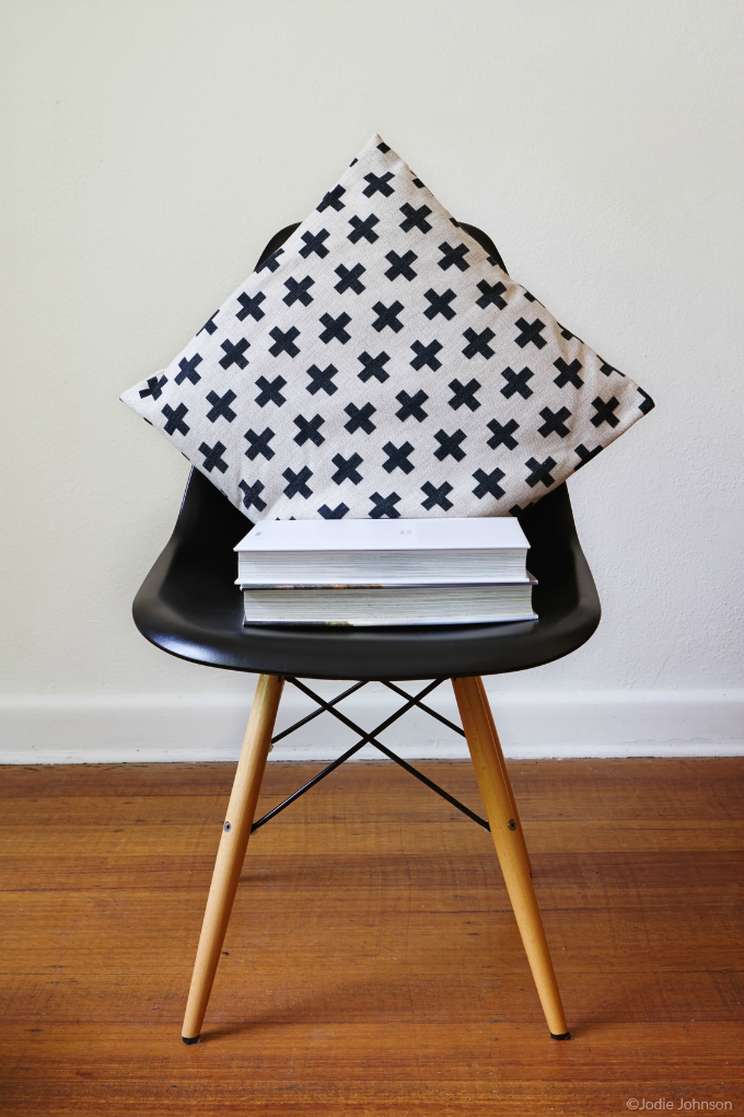 Black chair with black and white pillow and stack of books - photo copyright Jodie Johnson