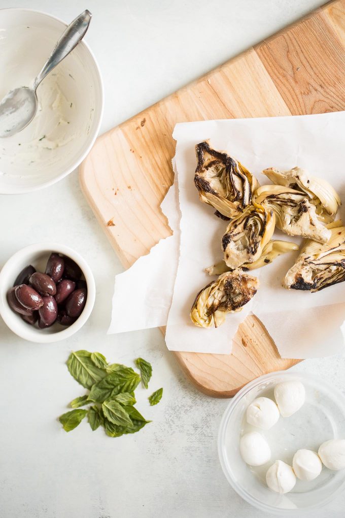 Grilled Artichoke, Olive and Pesto Flatbread Recipe - It's lighter than pizza (423 calories) and makes a better appetizer, too! Topped with kalamata olives, grilled artichokes, basil pesto, and mozzarella