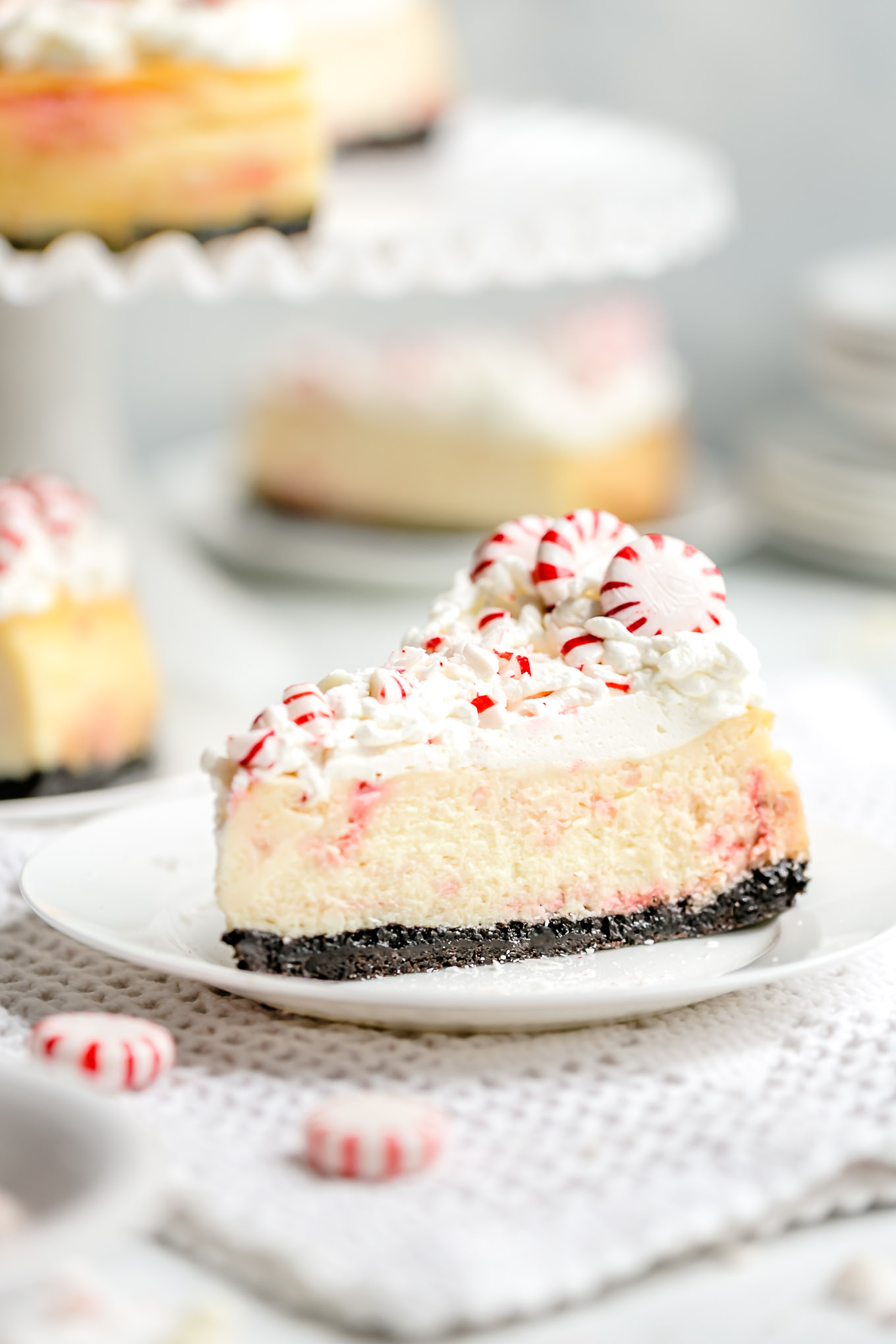 White Chocolate Peppermint Cheesecake - Smooth and creamy white chocolate cheesecake infused with cool peppermint flavor, a substantial chocolate cookie crust, and a cloud cover of whipped cream make this cheesecake recipe the holiday season's best, most beautiful dessert! 